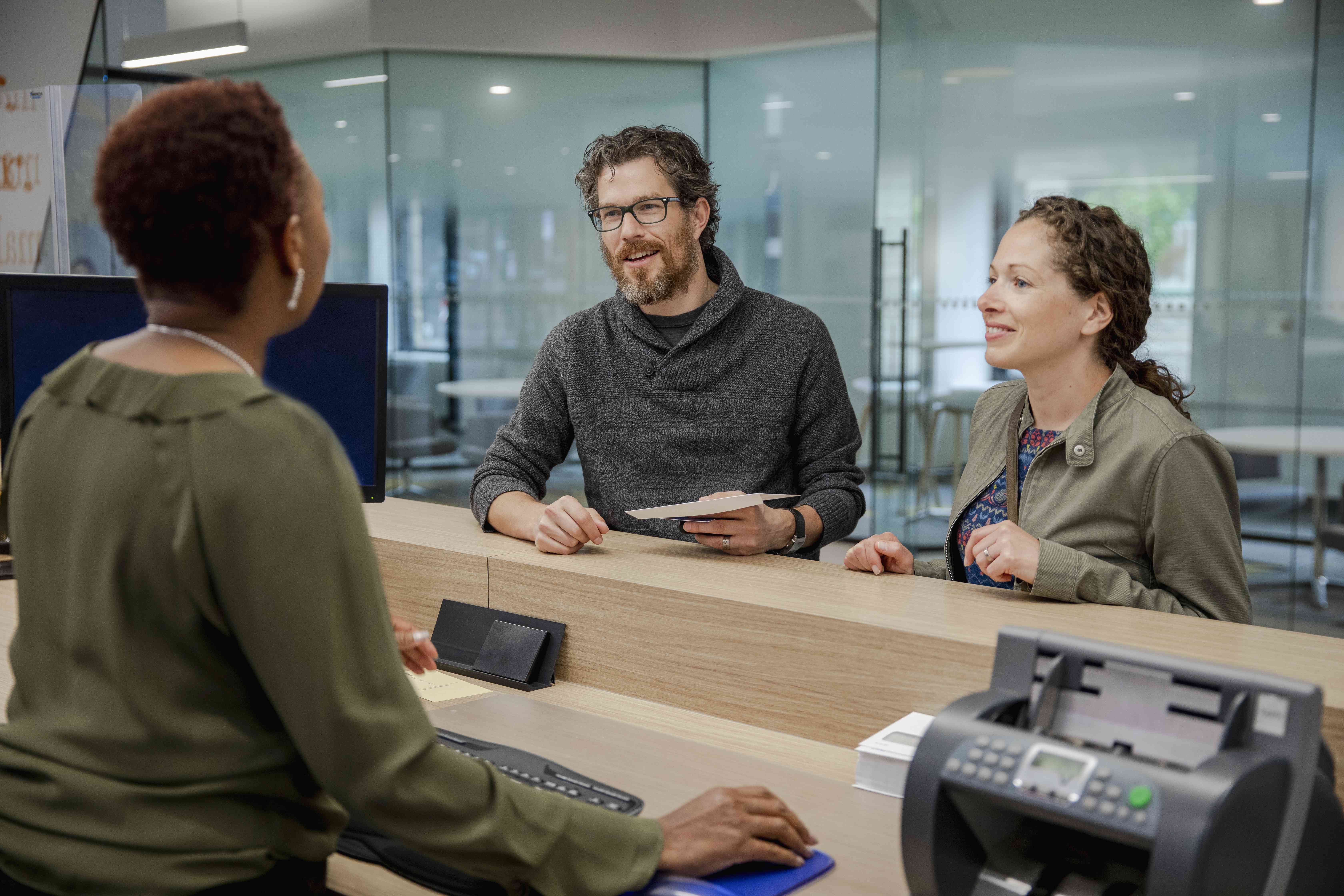 A couple in a bank talks to a teller.