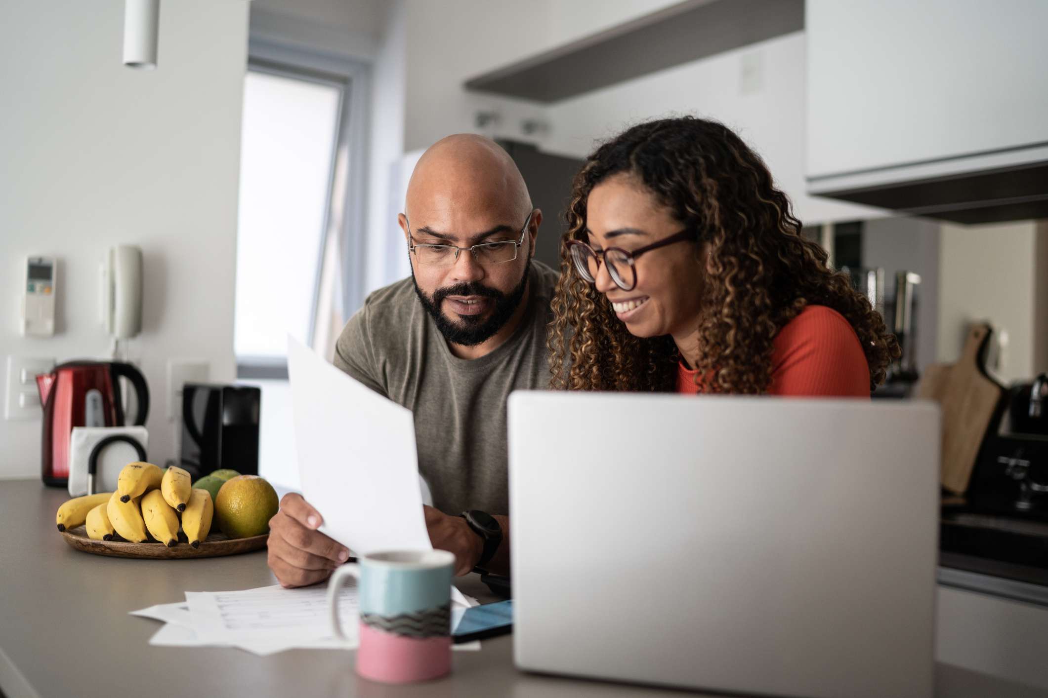 A couple review documents at a kitchen table.