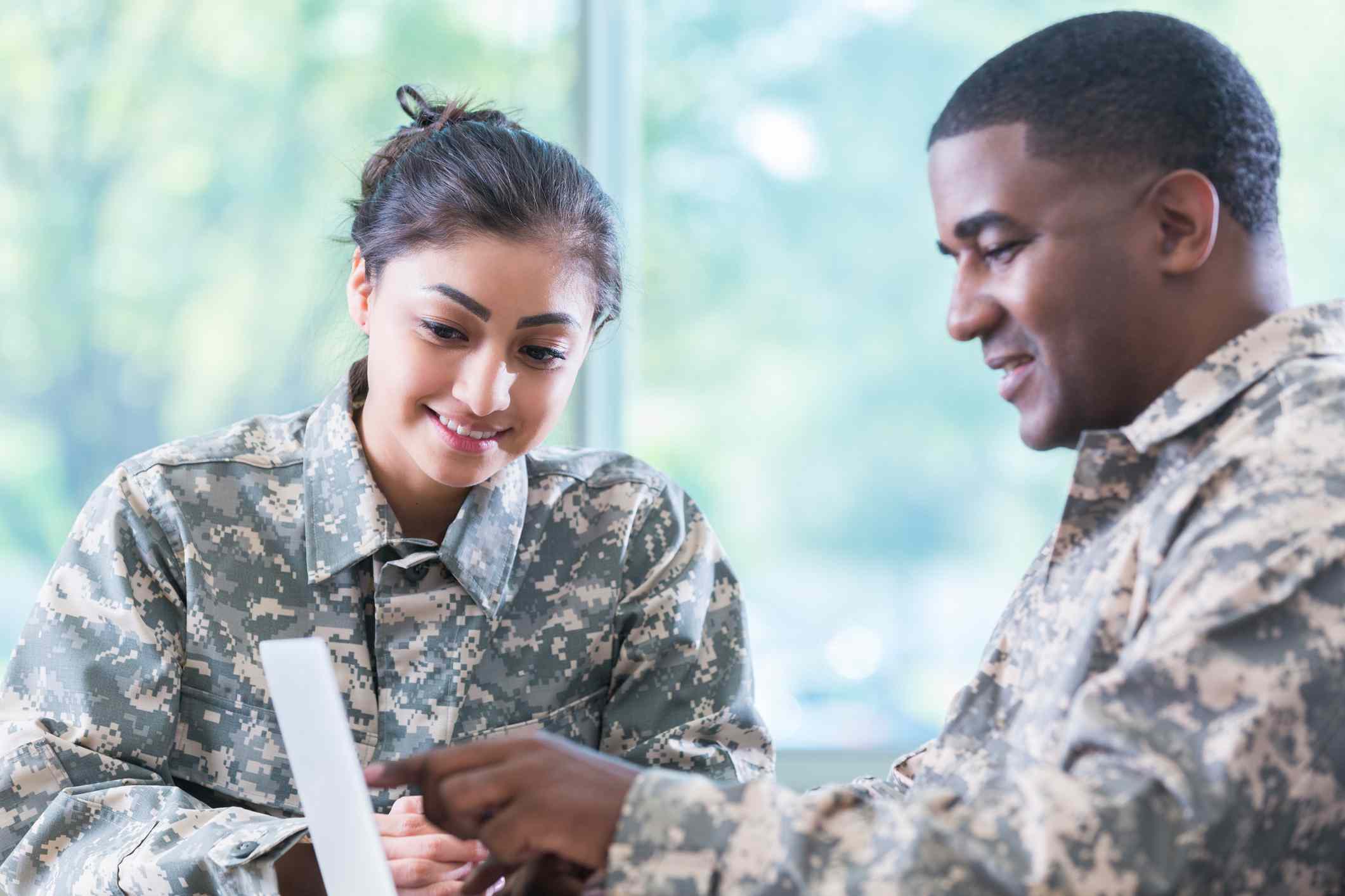 Two veterans discuss information on a laptop.