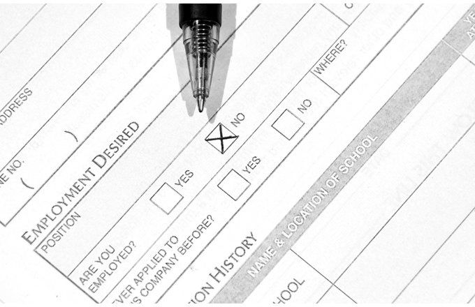 Pen on application form checking "NO" to the question "Are you employed?"