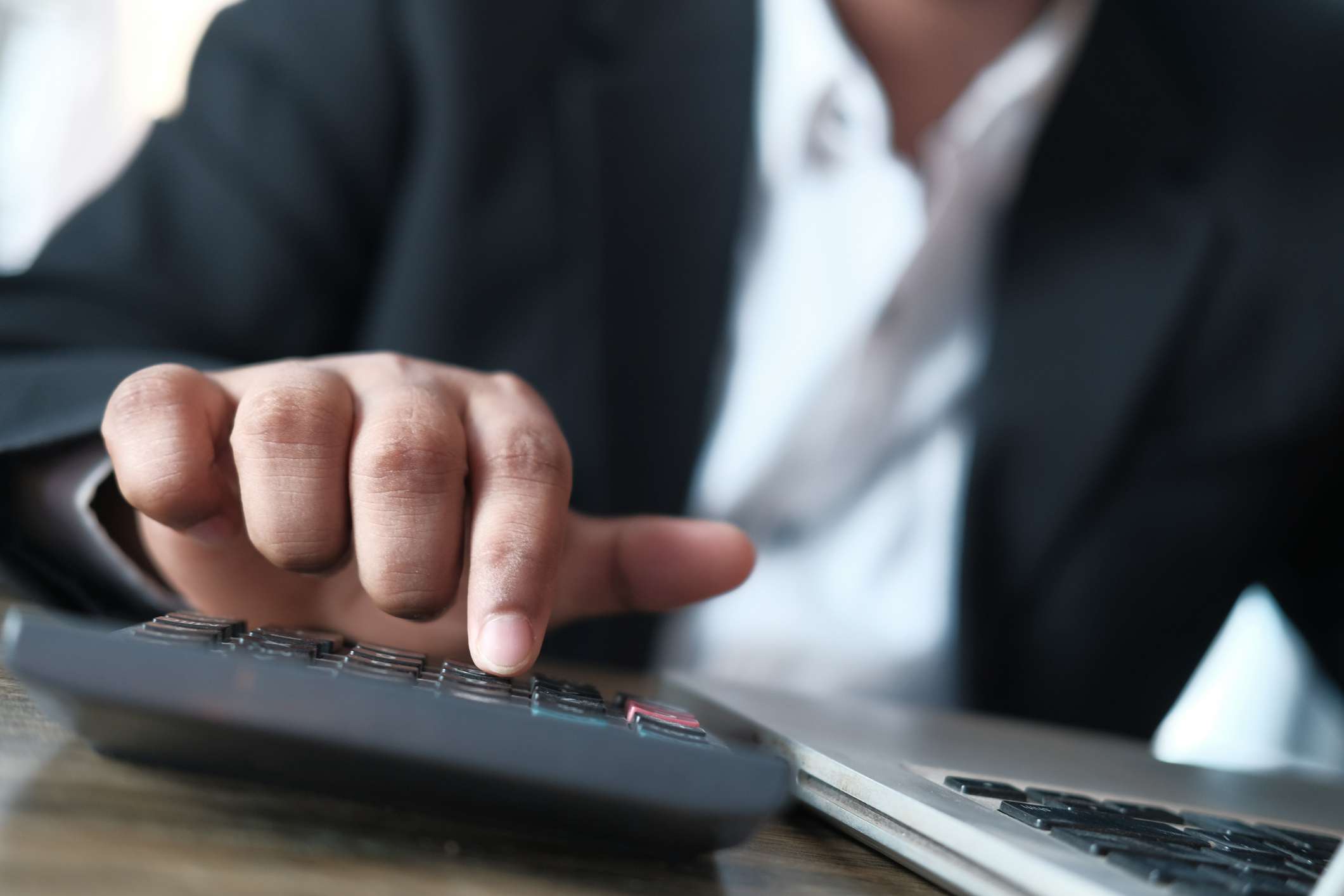 A businessman hand using calculator for calculating cost.