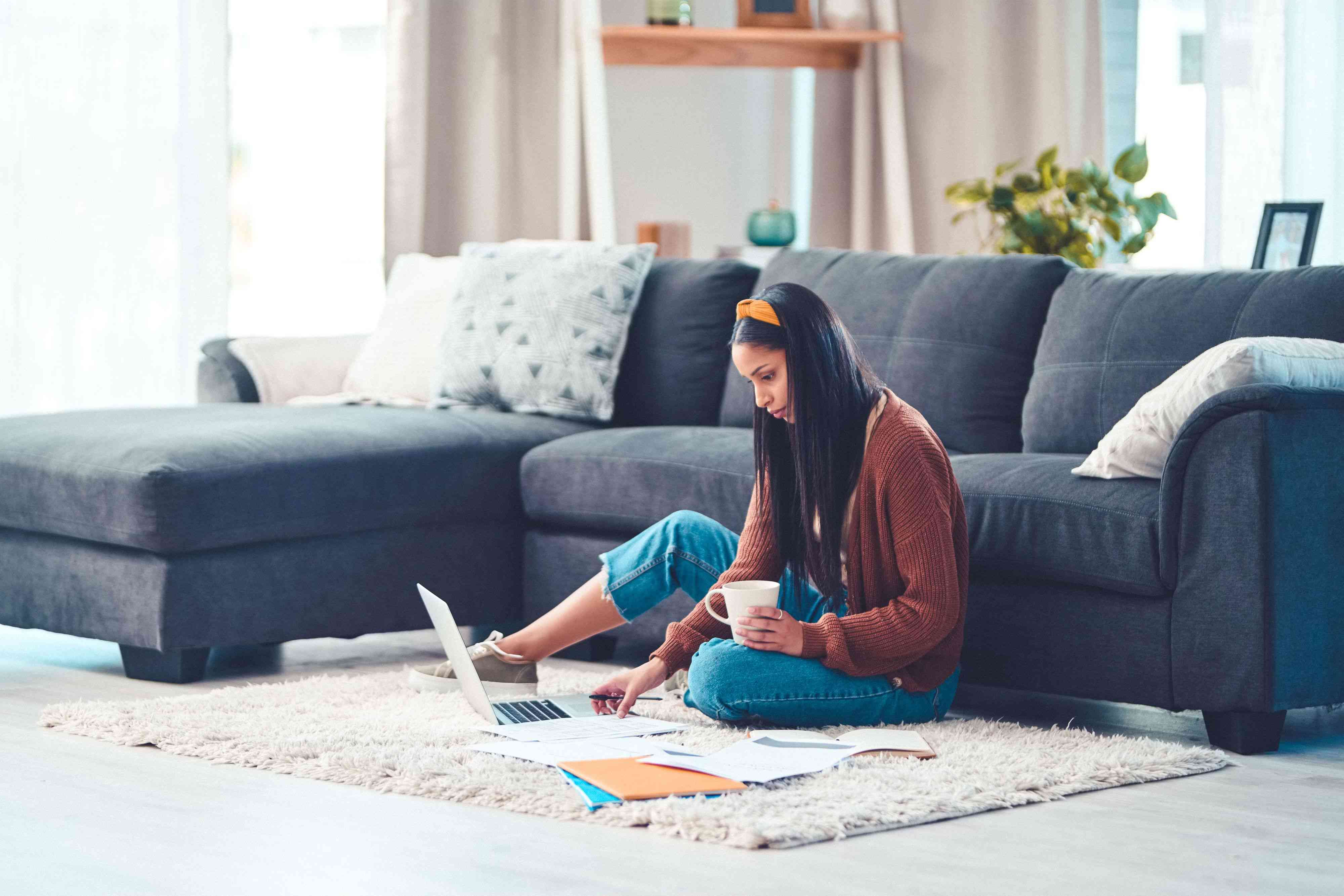 A young woman uses a laptop on the floor.