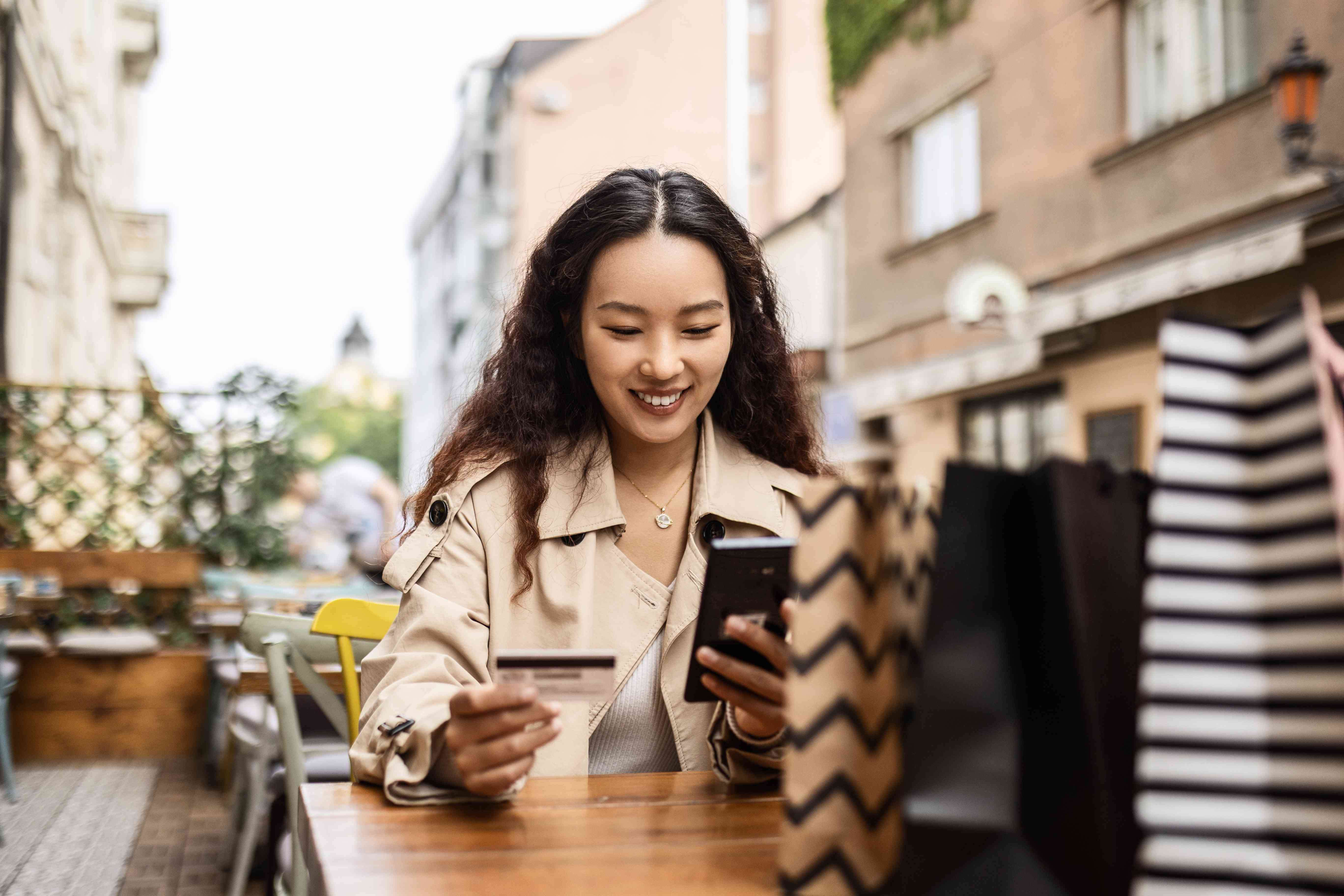 Woman in cafe with shopping bags paying with a credit card