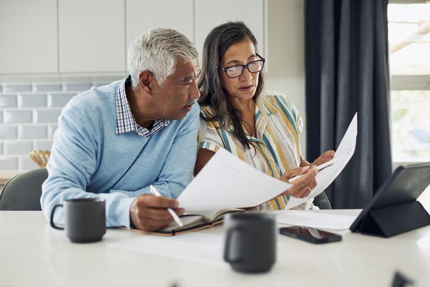 A couple reviews their finances together at the kitchen table. 