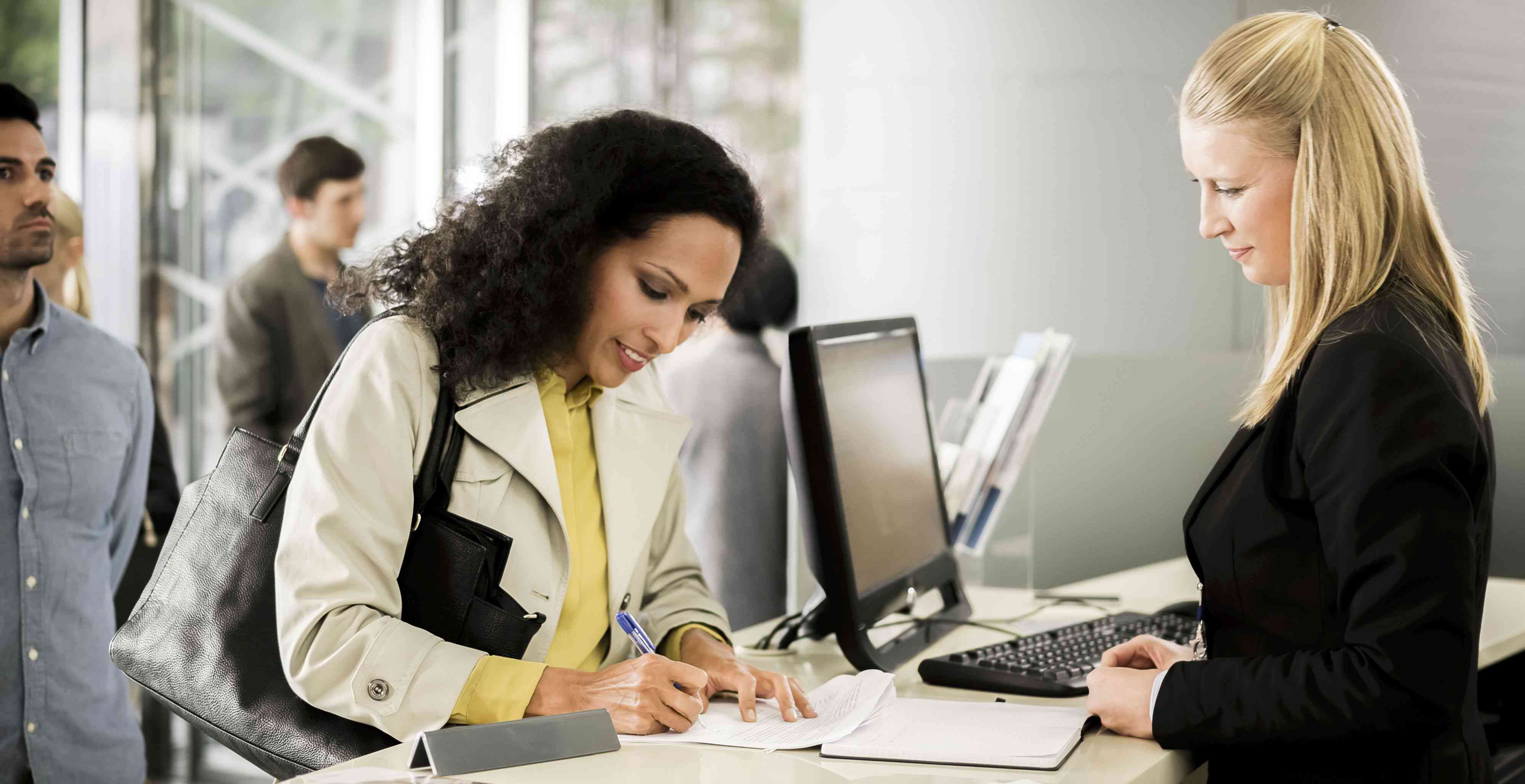 Customer signing a document at the window of a bank teller