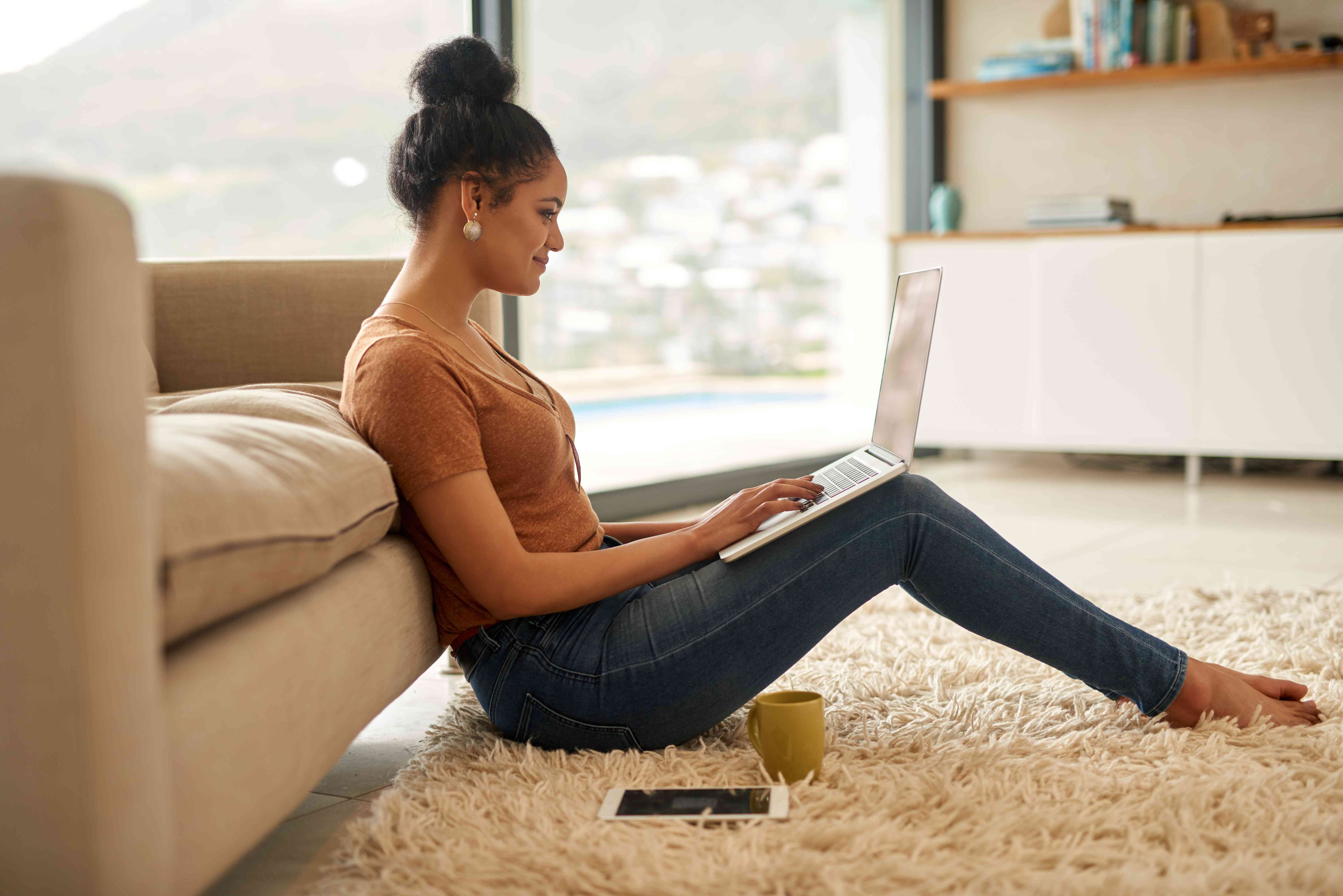 Young woman sitting in her living room and doing her online banking on a laptop