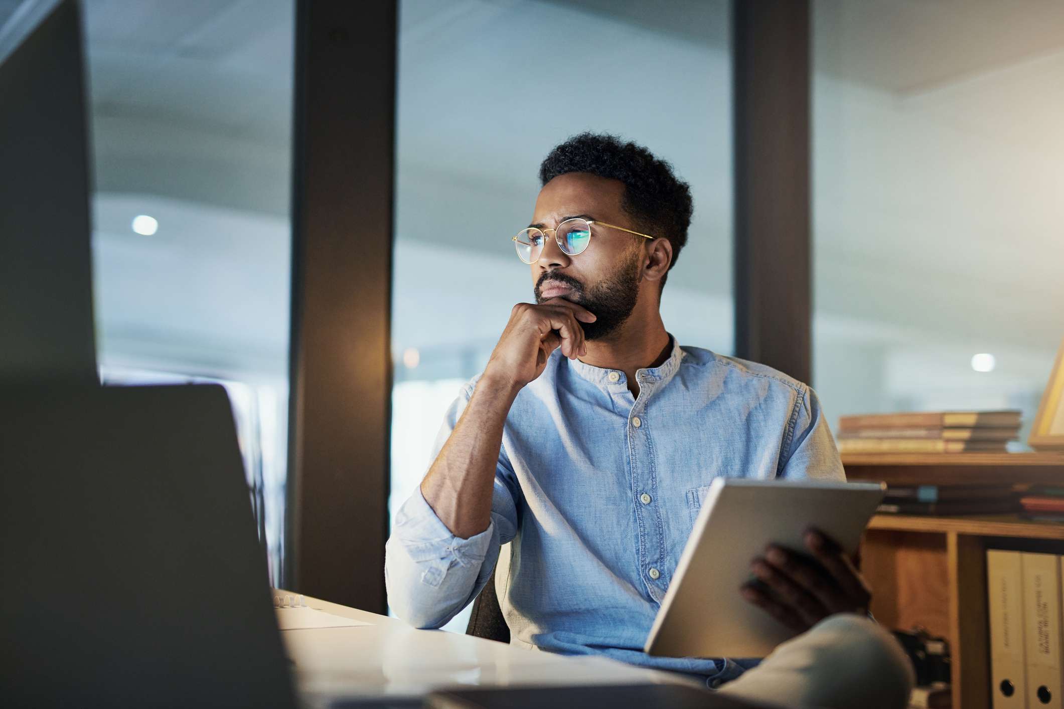 A man looks thoughtful while working at a desk.