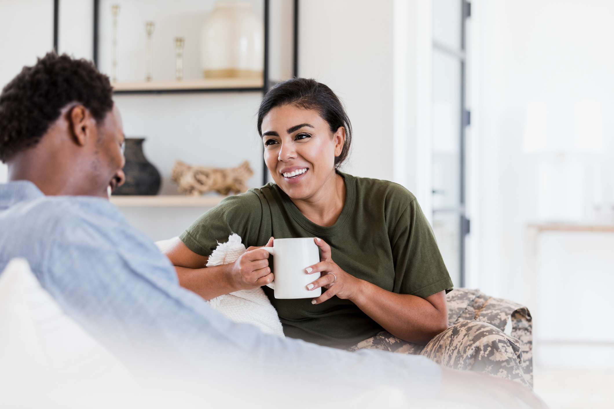 Veteran sits on couch, holding coffee.