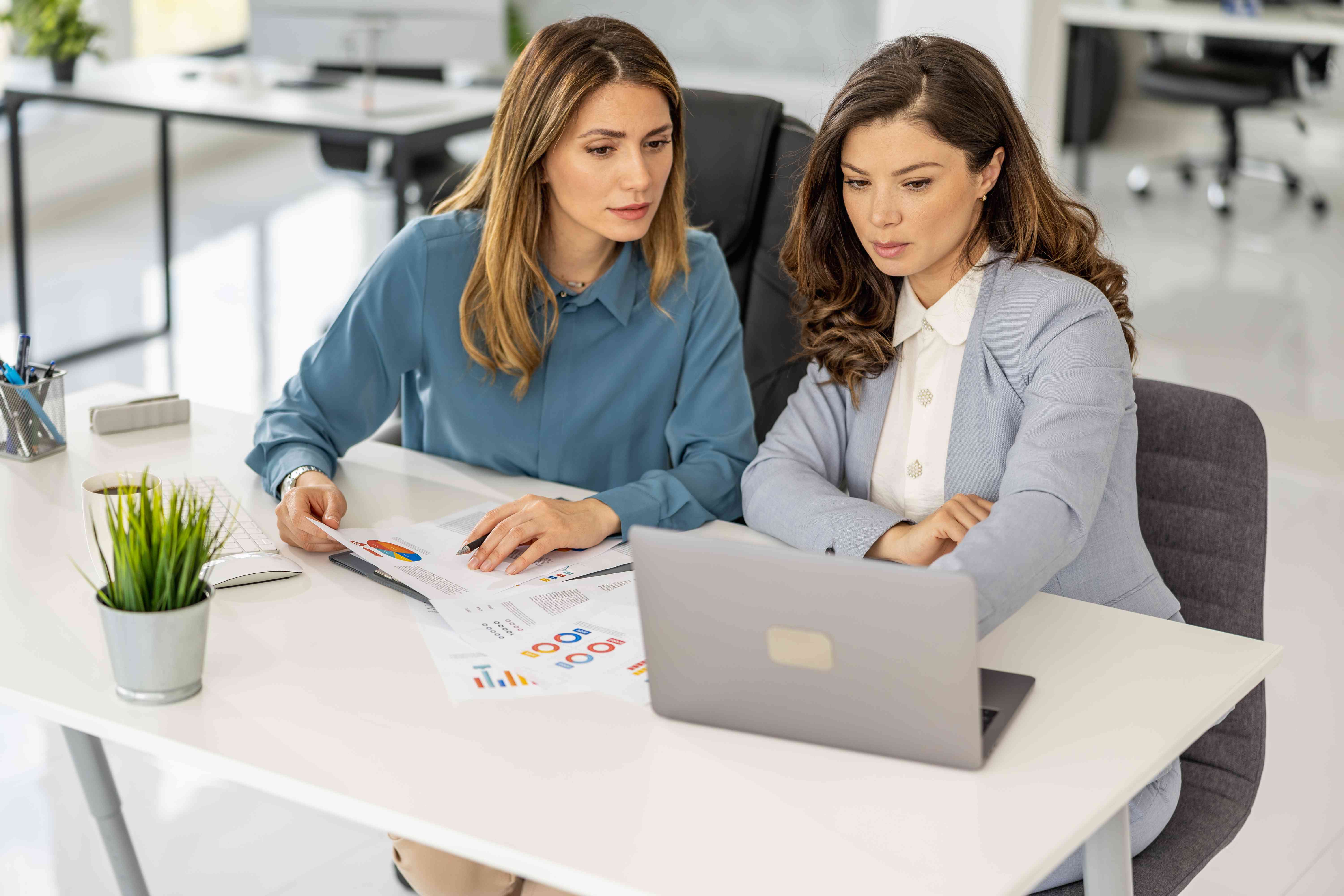 Two female businesswomen working together on a company project to issue CDs at the office